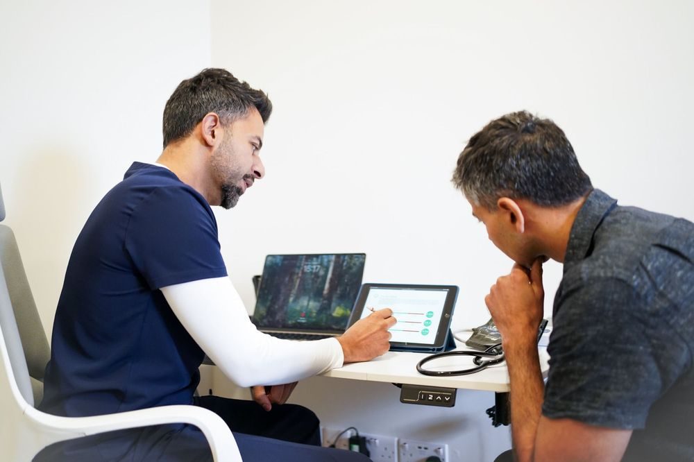 Private Health Screening Birmingham Dr Bik going through test results on an iPad with a patient